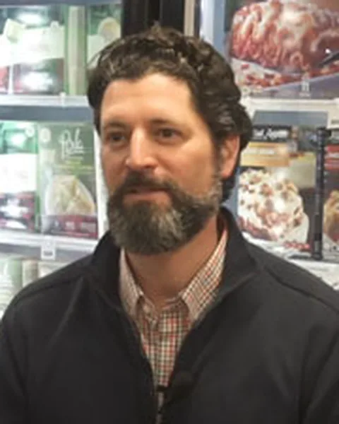 Mike Giebelhausen, bearded, in a dark jacket, in a grocery aisle.